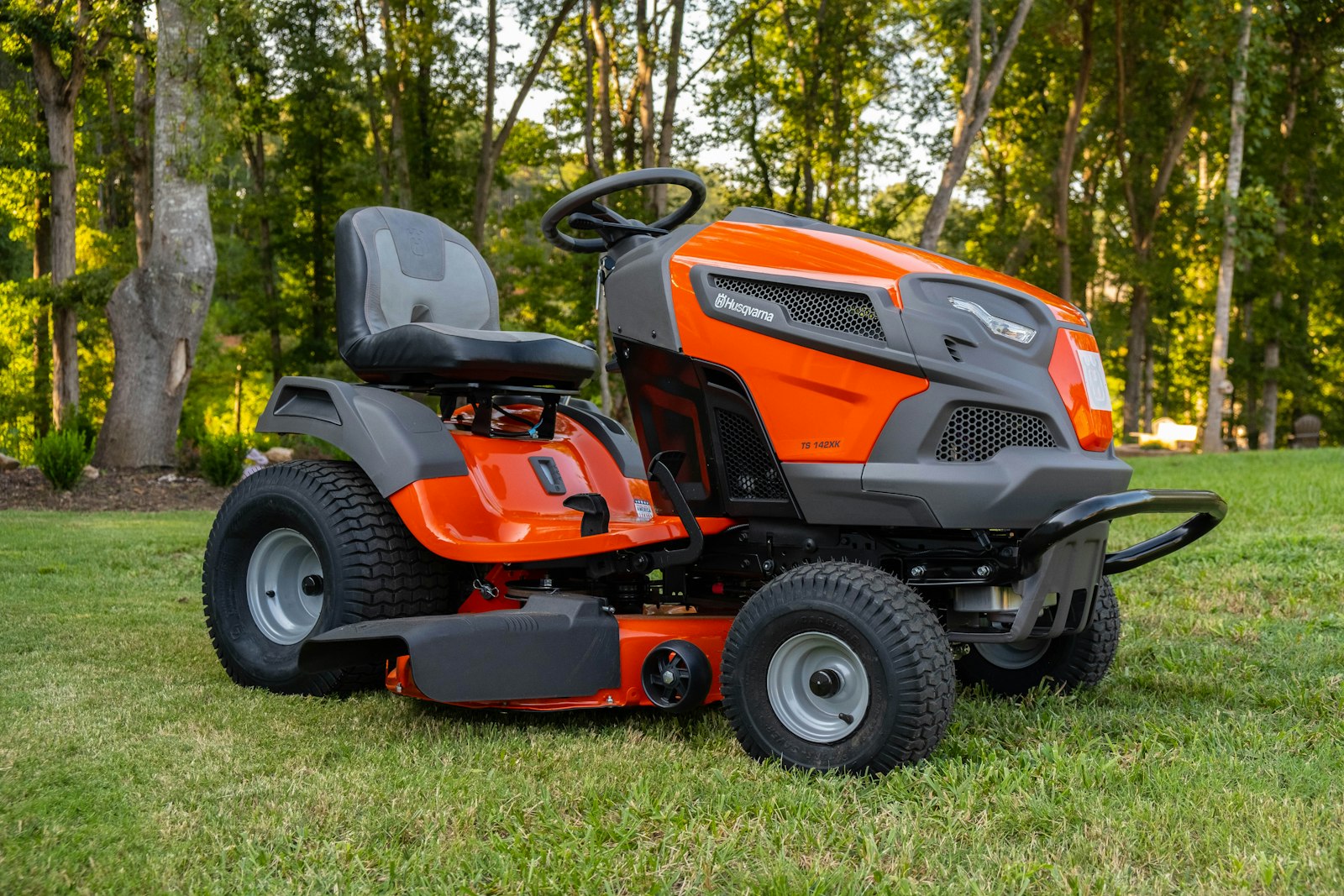 Orange zero-turn mower cutting a stripe across a residential lawn.